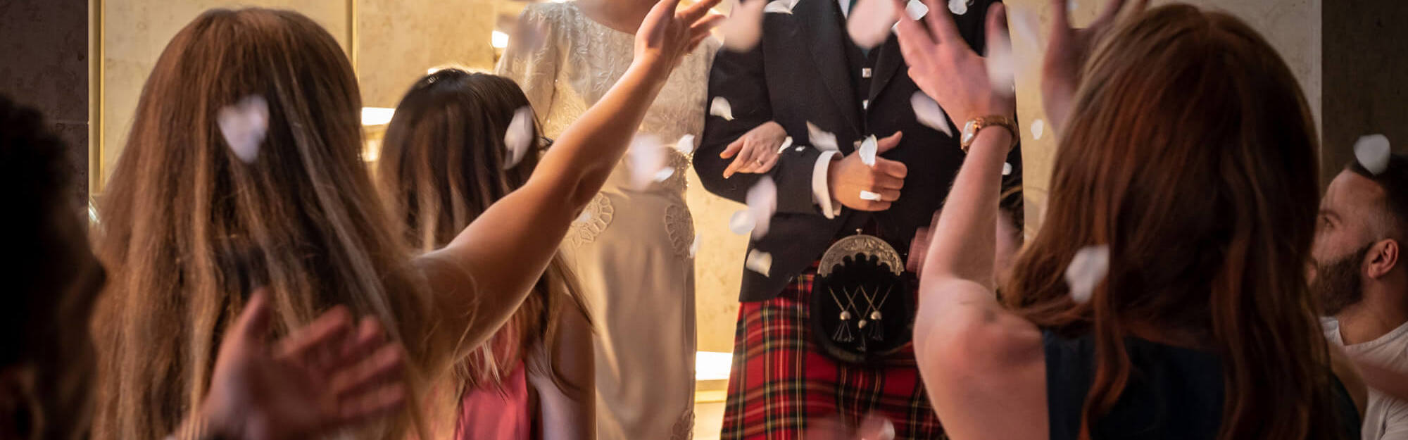 Bride and groom with crowd throwing confetti
