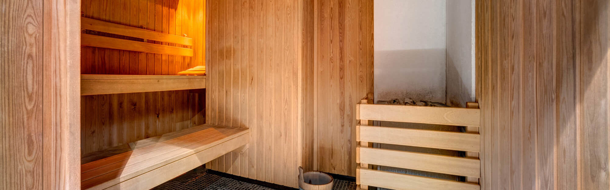 Sauna with blue and white floor tiles and wooden wall panels and seating