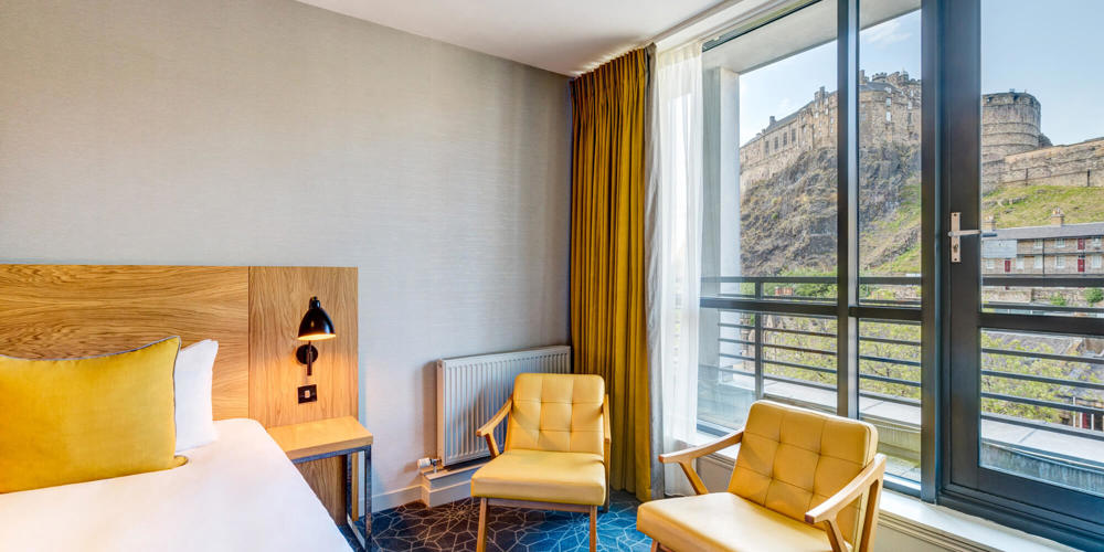 Double bed with views onto Edinburgh Castle in Apex Grassmarket's Deluxe Castle View Room