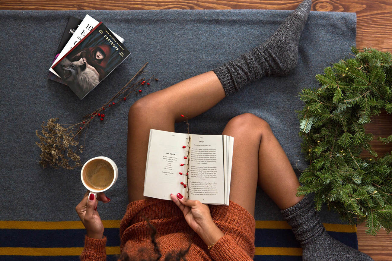 Person reading a book wearing fluffy socks, holding a cup of tea