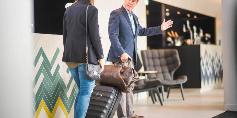 Male employee helping female guest with her bag in hotel