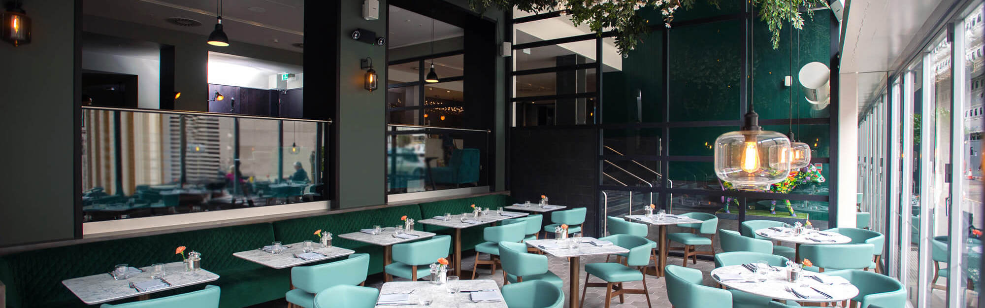 Tables and chairs set up under the floral canopy at The Lampery