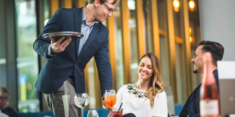 Couple of guests being served drinks by waiter